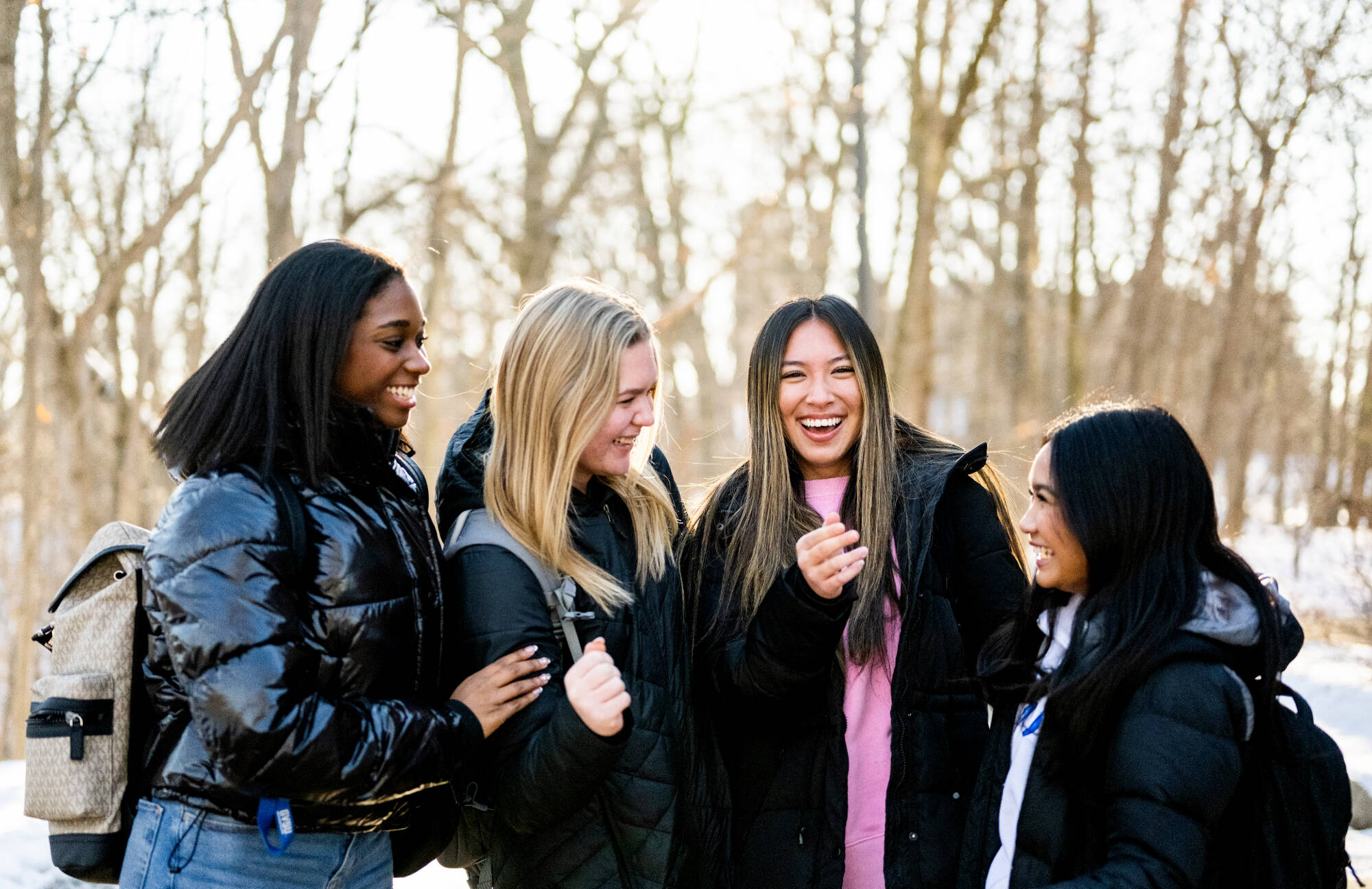 4 GVSU students huddled outside smiling and laughing